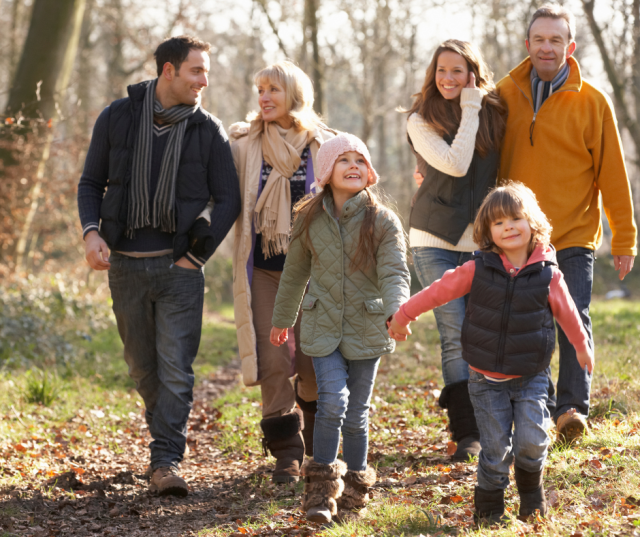 Une famille (grands-parents, parents et enfants) se promène dans les bois en Belgique, sereins car leur planification de succession a été réglée par leur notaire.
